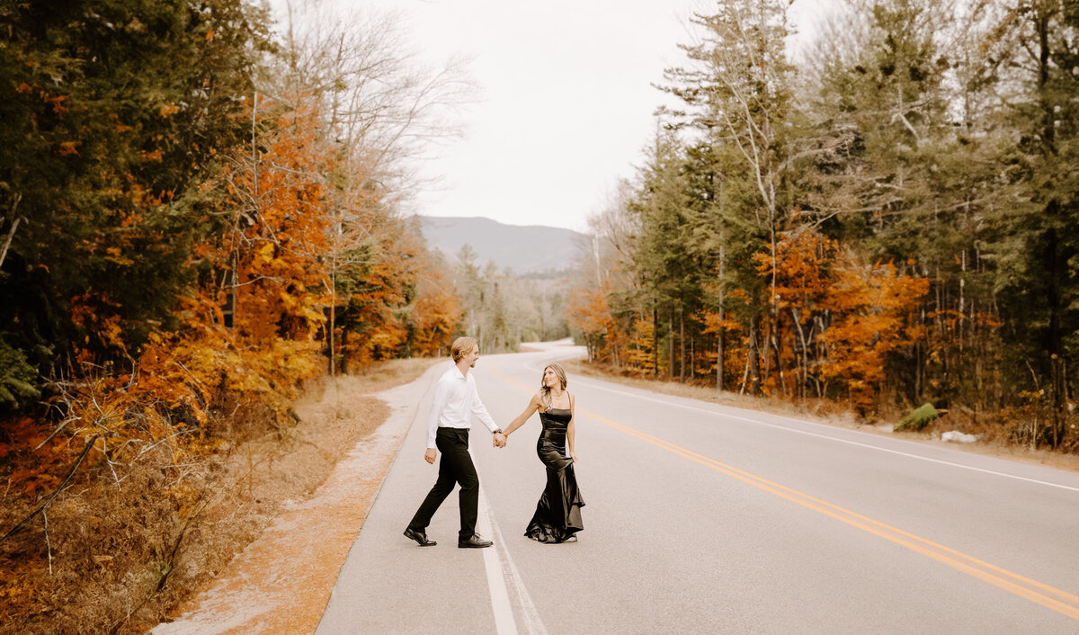 couple walking across a road holding hands in the fall