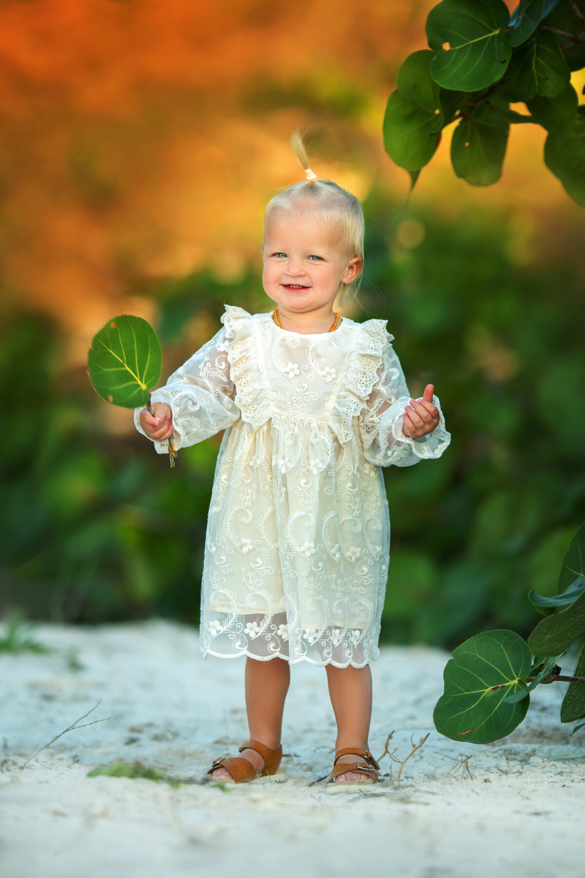 Stylish baby girl in vintage inspired lace dress  on white sand beach