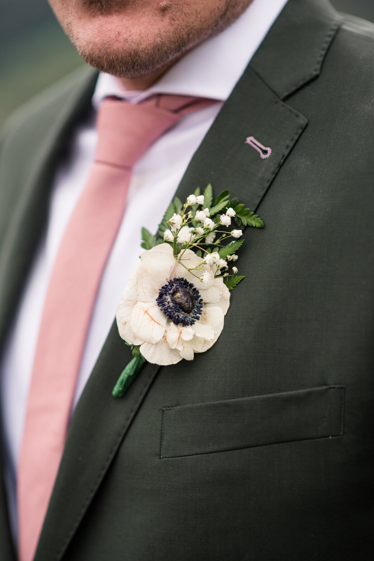 detail shot of grooms boutonnière pinned onto his grey suit for his rocky mountain national park wedding