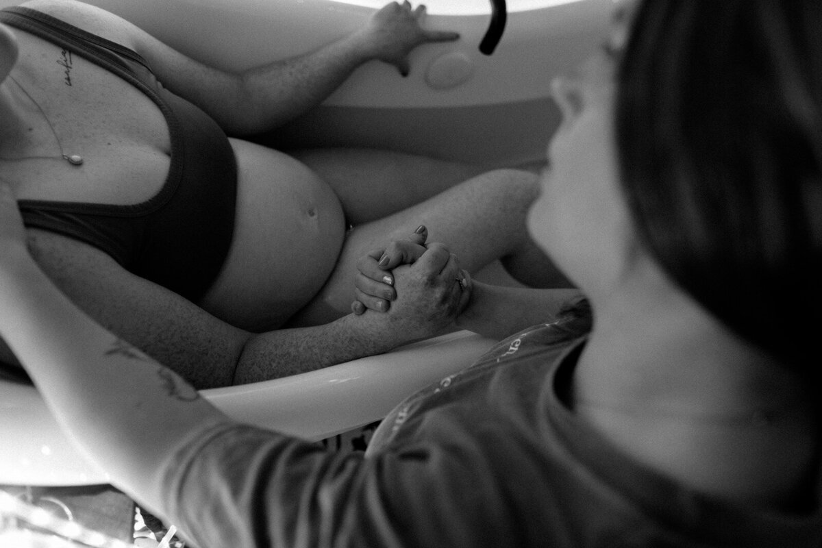 Close-up of pregnant woman being supported in a birth pool as Savannah explains her role as a doula.