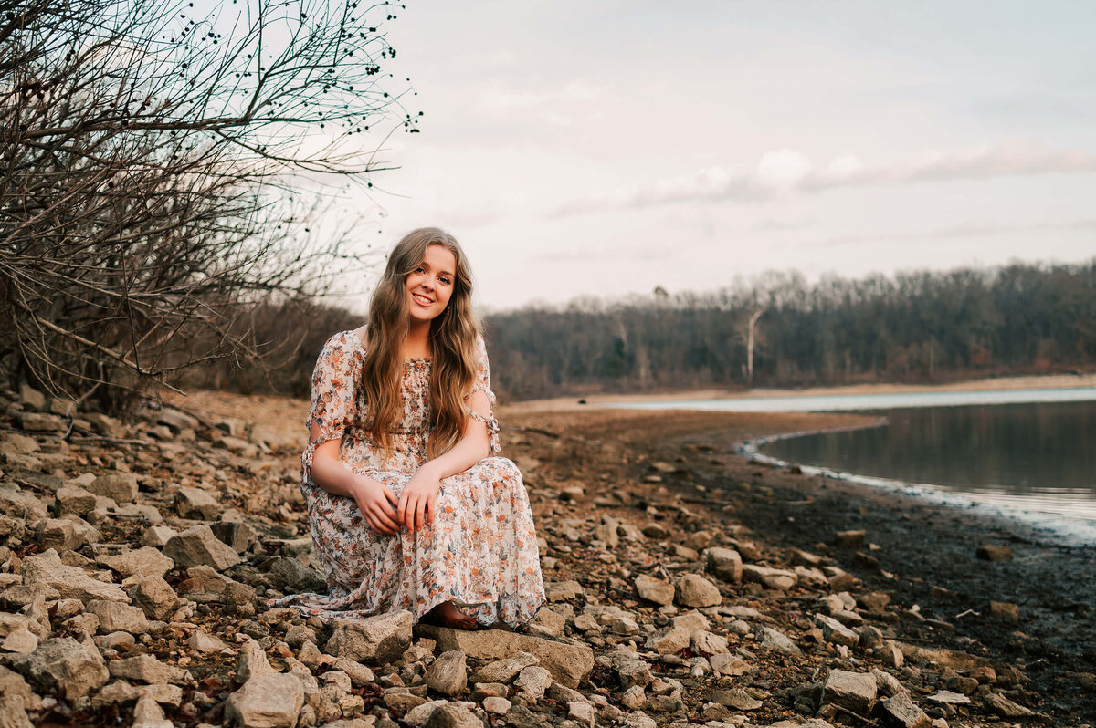 senior pictures in Springfield MO of high school senior girl sitting in rocks next to lake
