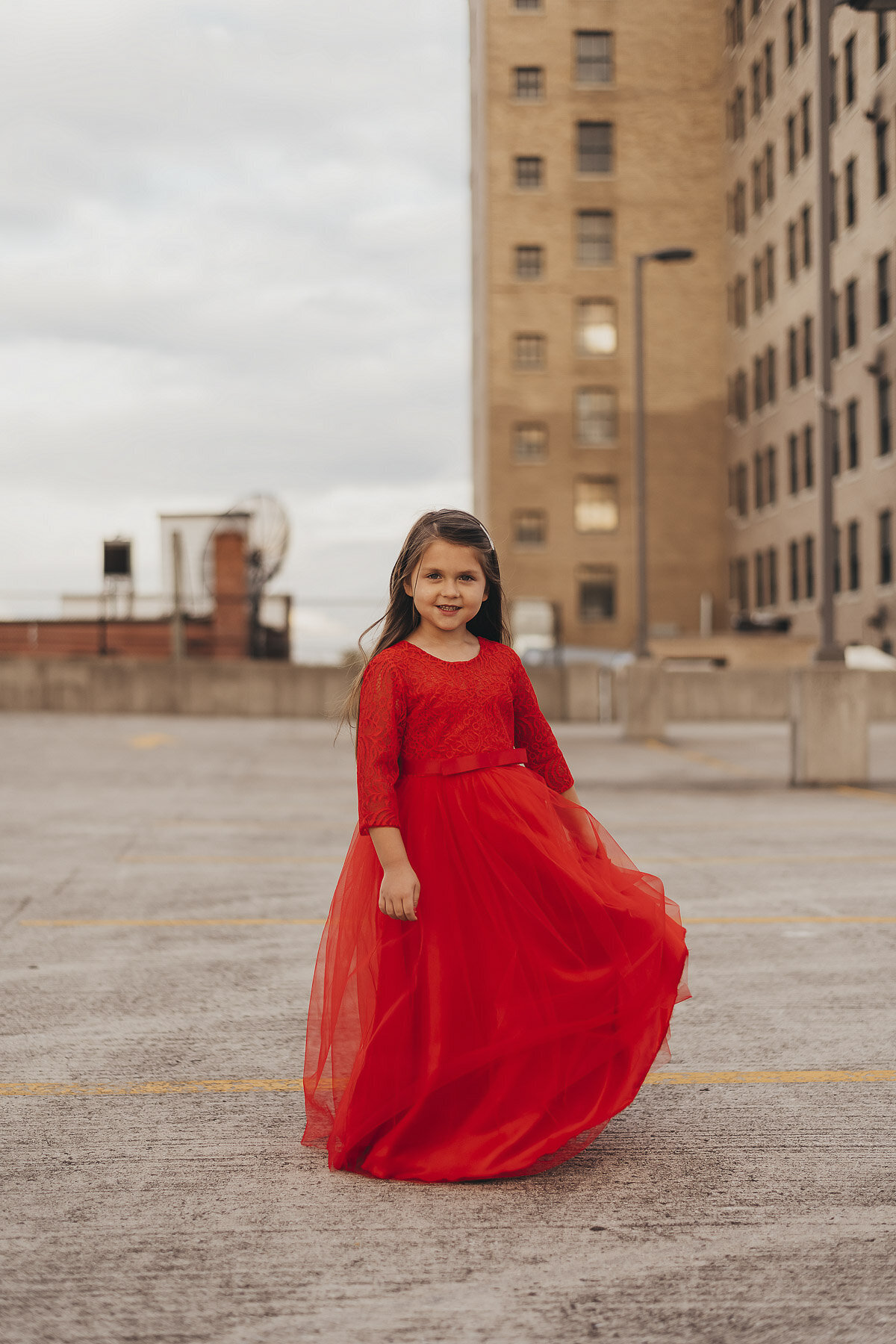 girl with brown hair in a long red dress in a city