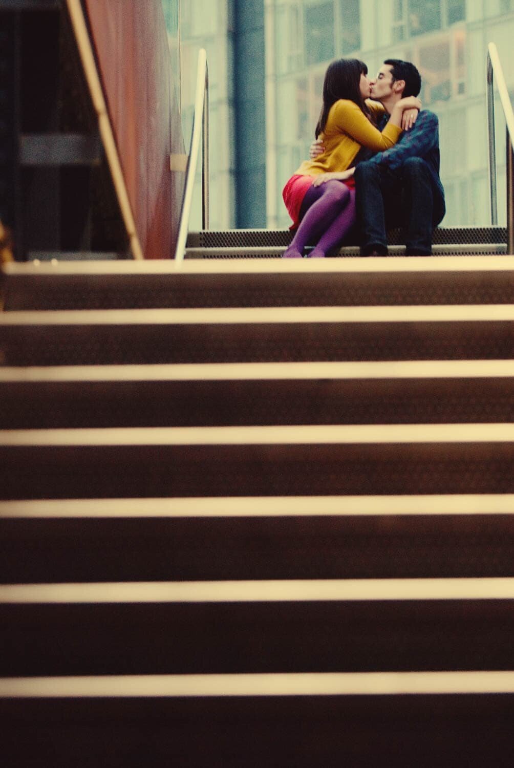 a colorful couple sit at the top of stairs and kiss in nyc