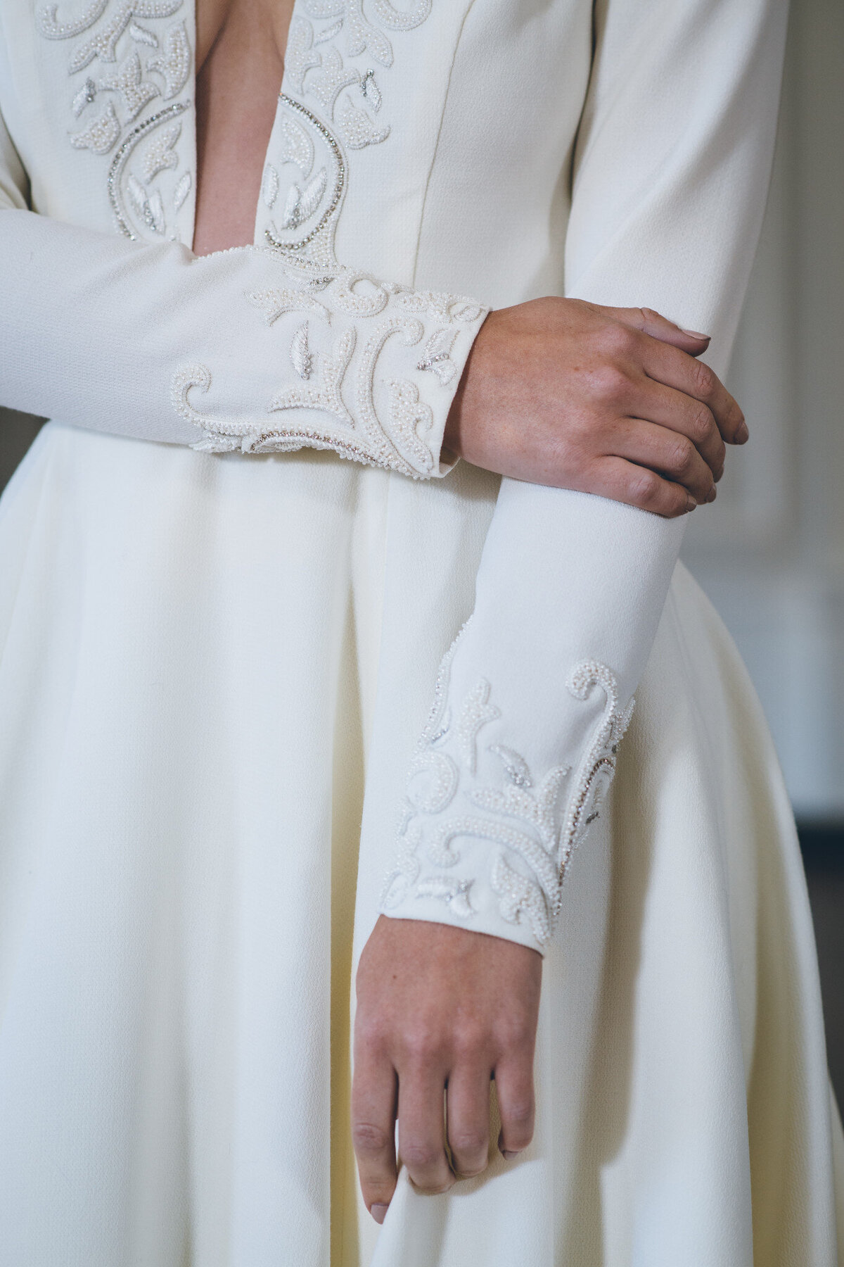 The same beaded embroidery motif of the neckline decorates the hem of the long sleeves on the Iman wedding dress style.