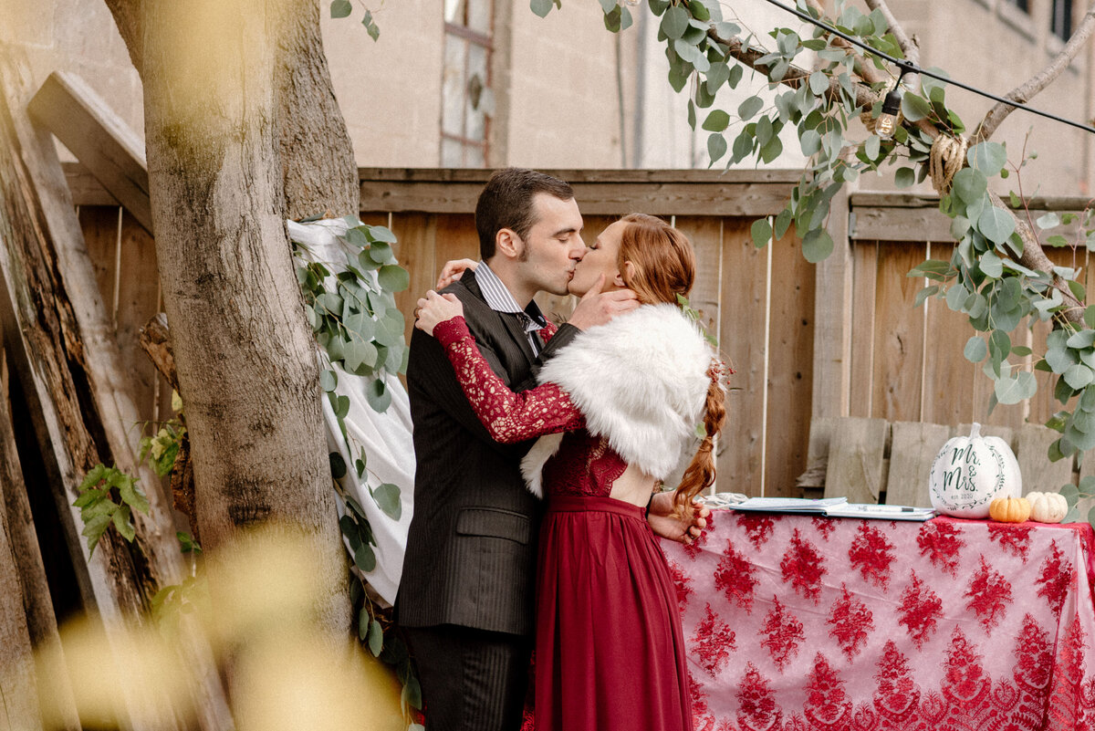 bride and groom share their first kiss during their backyard ceremony