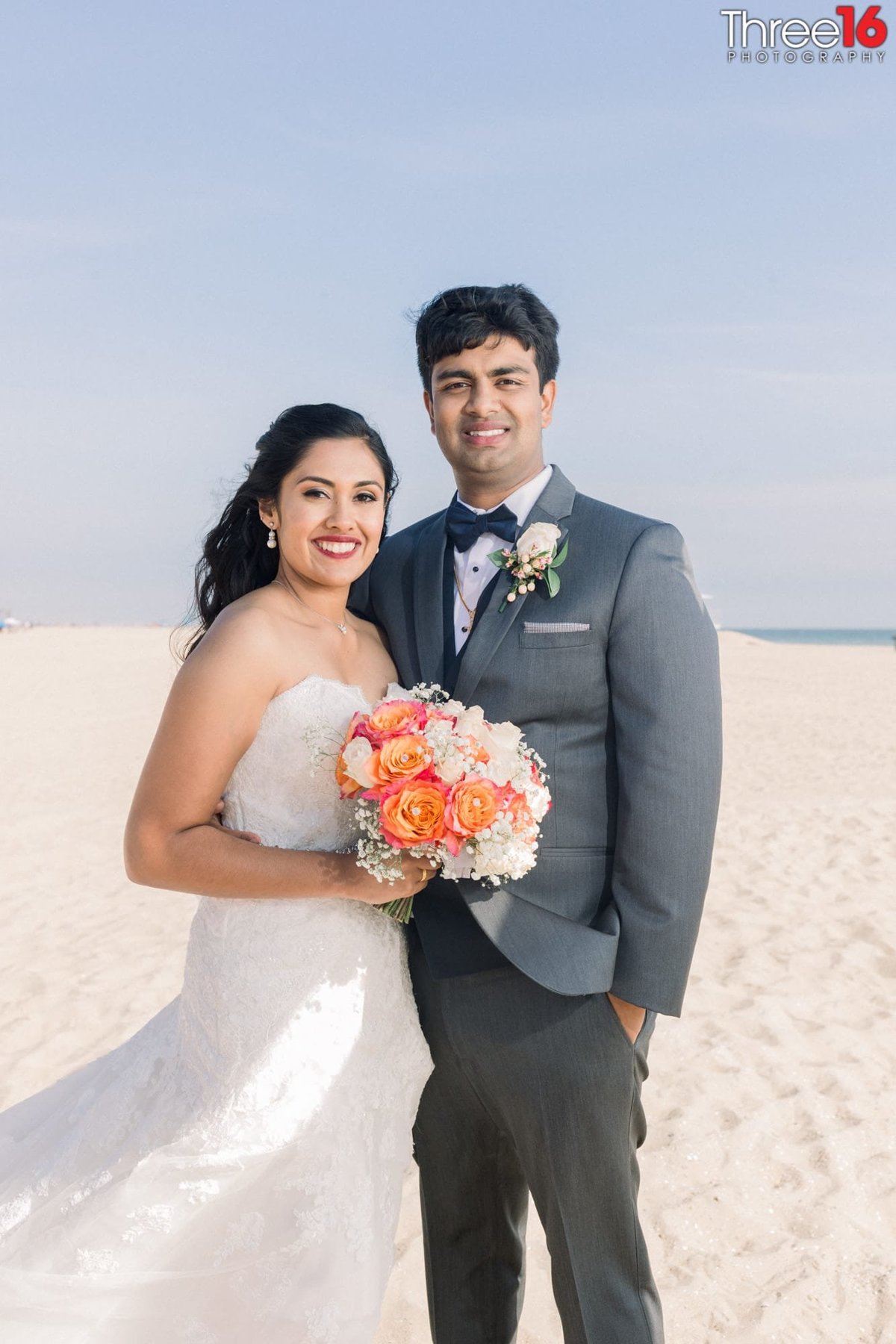 Bride and Groom pose together on the beach in Huntington Beach