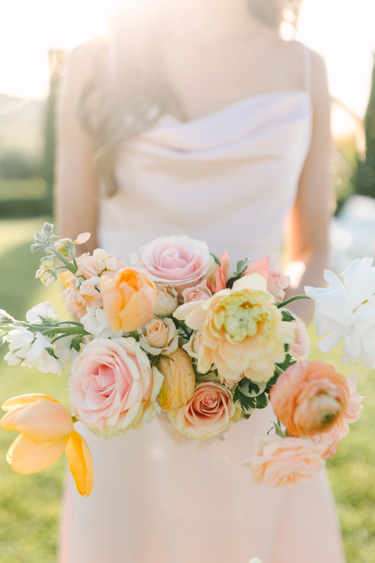 close up shot of bridesmaid bouquet filled with peach, coral, and soft orange flowers.