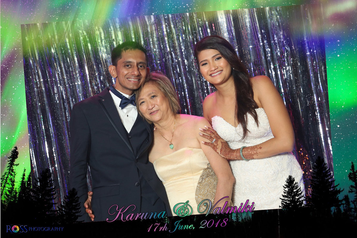 Older woman poses between groom and bride in commemorative photobooth image. Photobooth by Ross Photography, Trinidad, W.I..