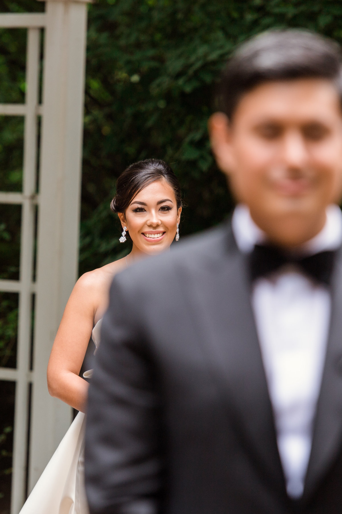 photo of brides smile with groom blurred out before first look during wedding at The Garden City Hotel