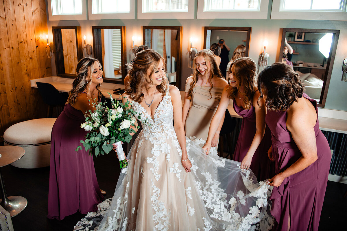 Bridesmaids helping bride primp her dress before the first look