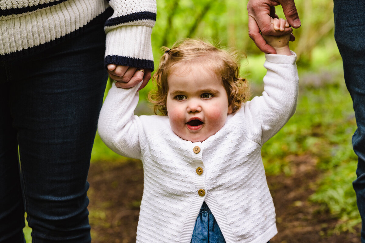 Little girl holding parents hands during family photoshoot