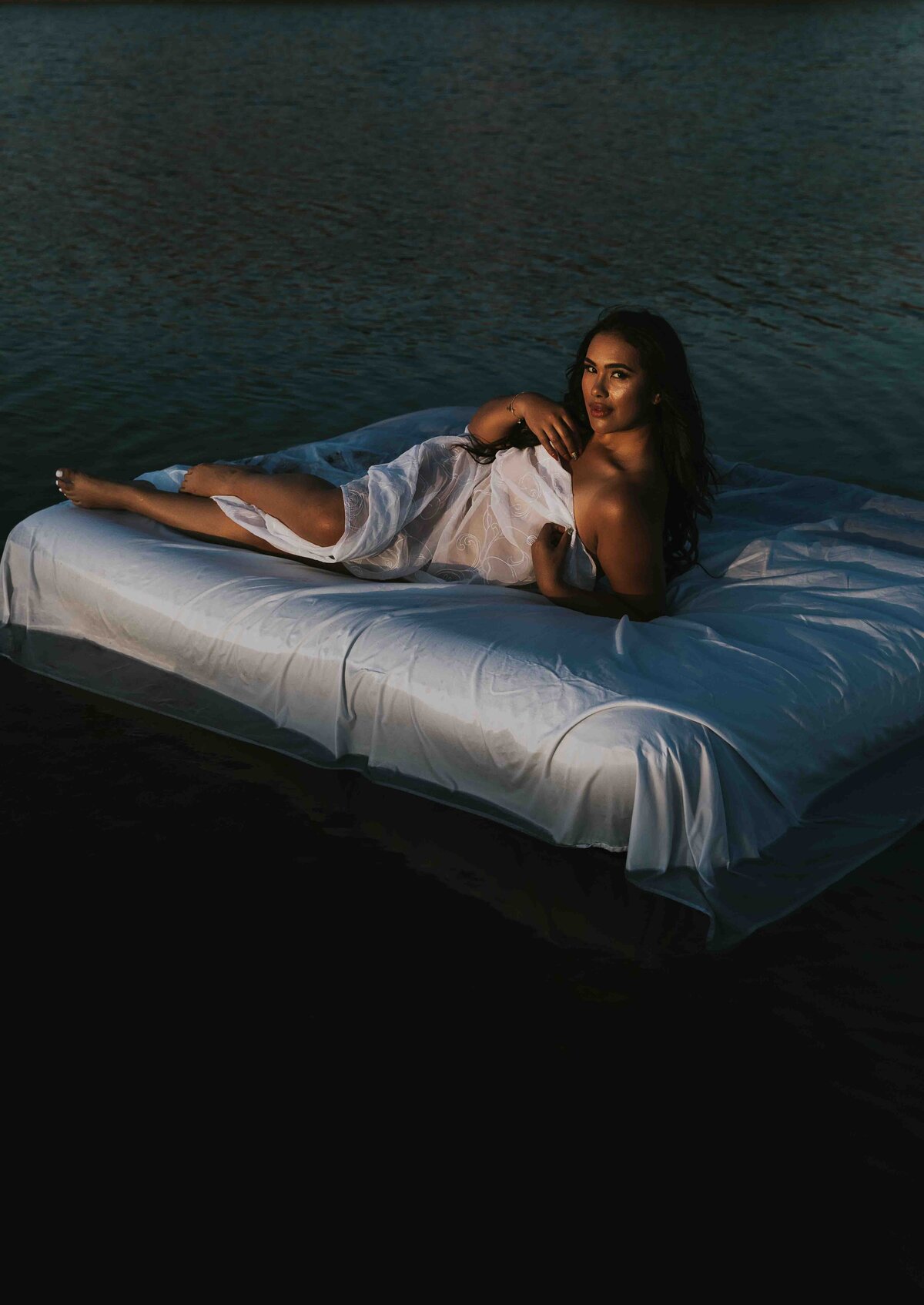 woman laying on a bed in the middle of a lake