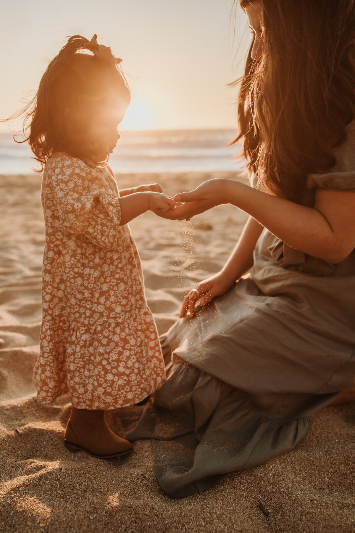 Mother and daughter portrait touching hands at sunset on California beach