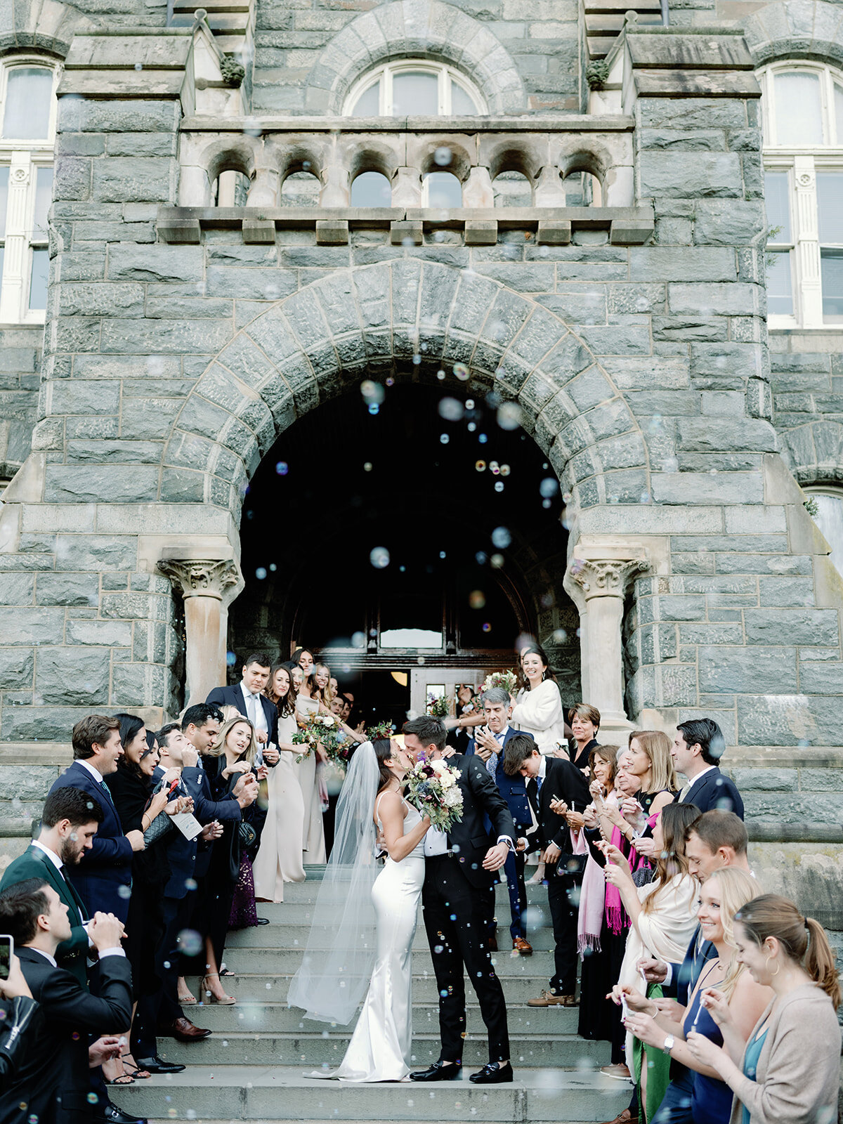 bride and groom kiss in front of guests in front of Dahlgren Chapel