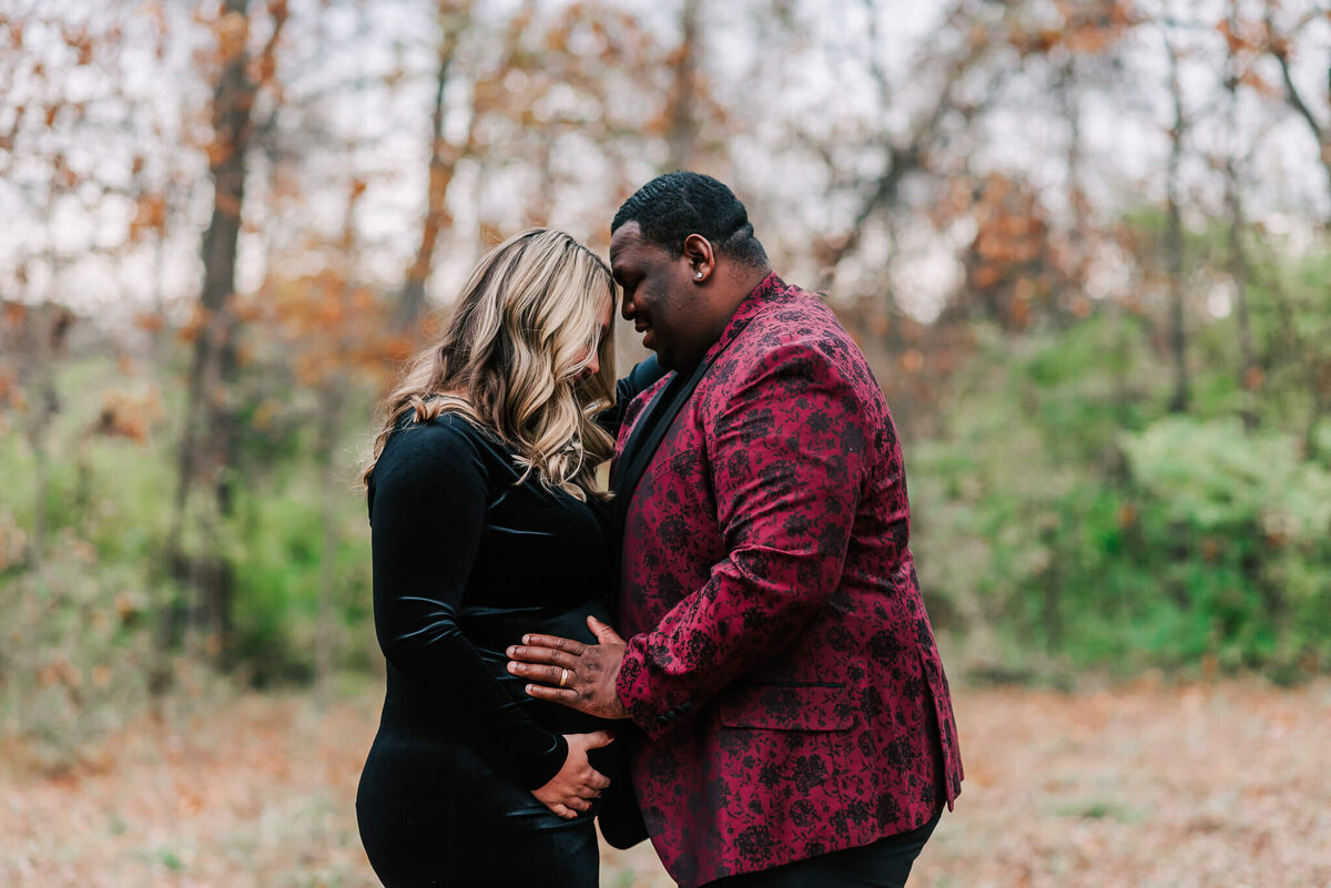 A couple's profile of them forehead-to-forehead holding the woman's bump