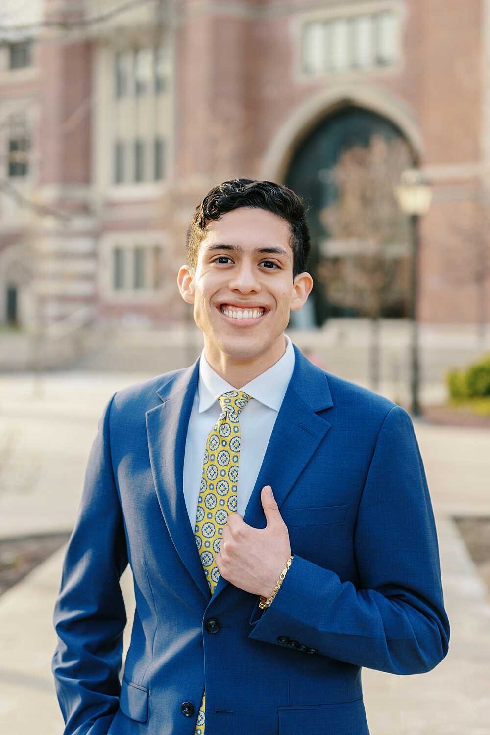 graduating Senior guy wearing a blue suit on his university campus