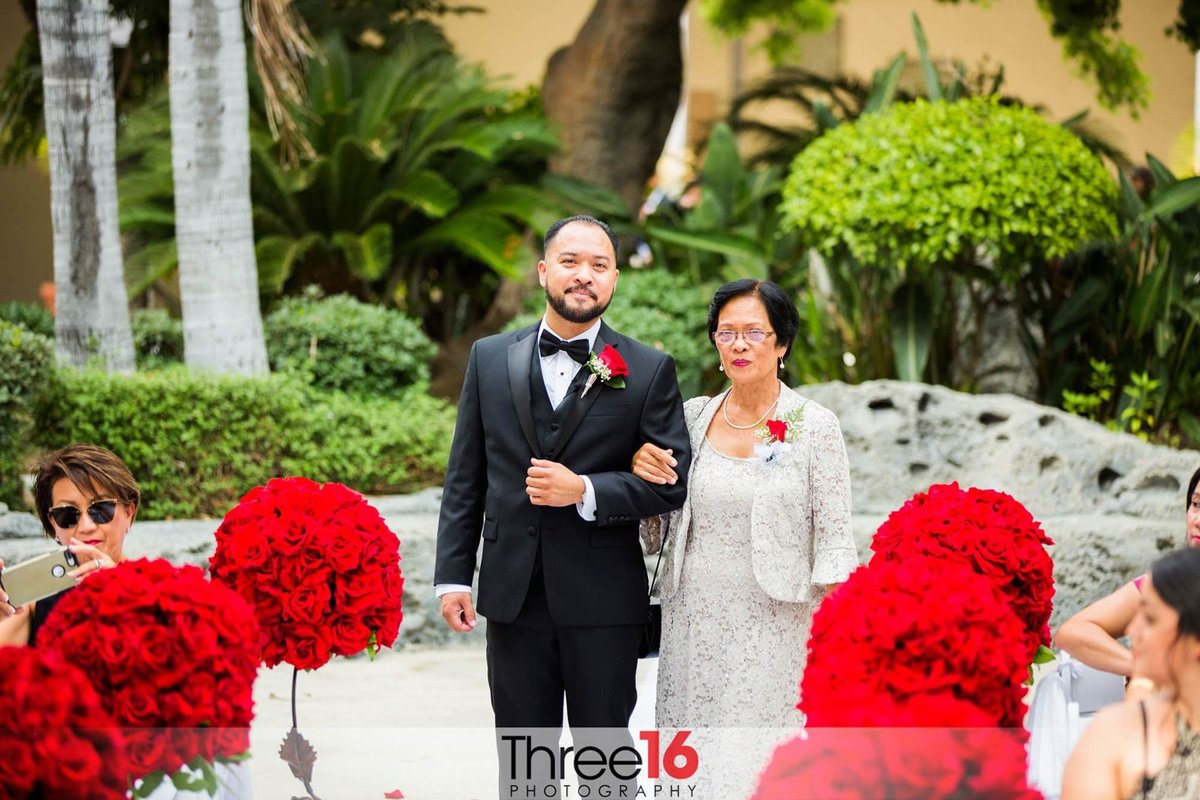 Groom escorts his mother up the aisle
