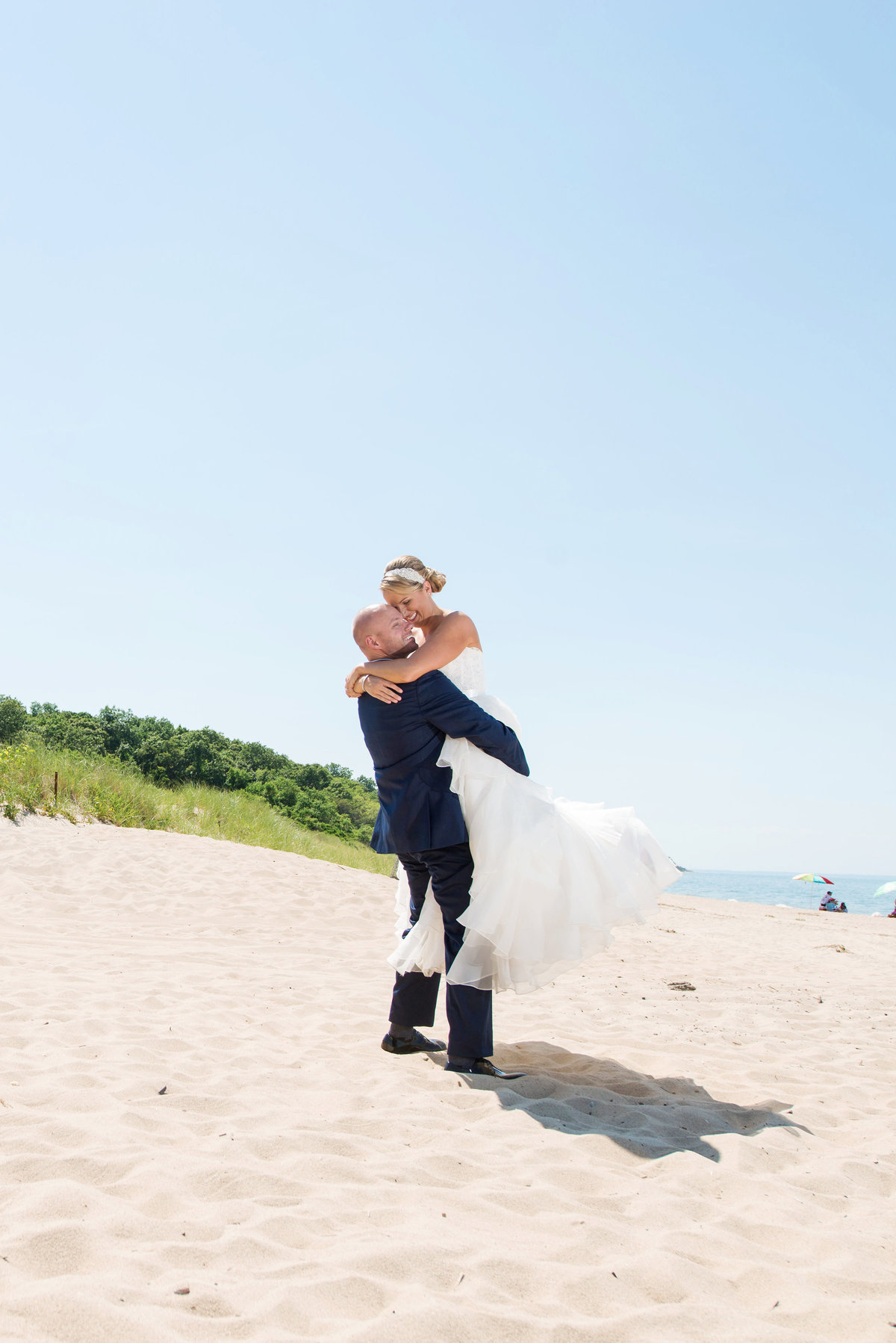 photo of groom carrying bride on the beach from wedding reception at Pavilion at Sunken Meadow