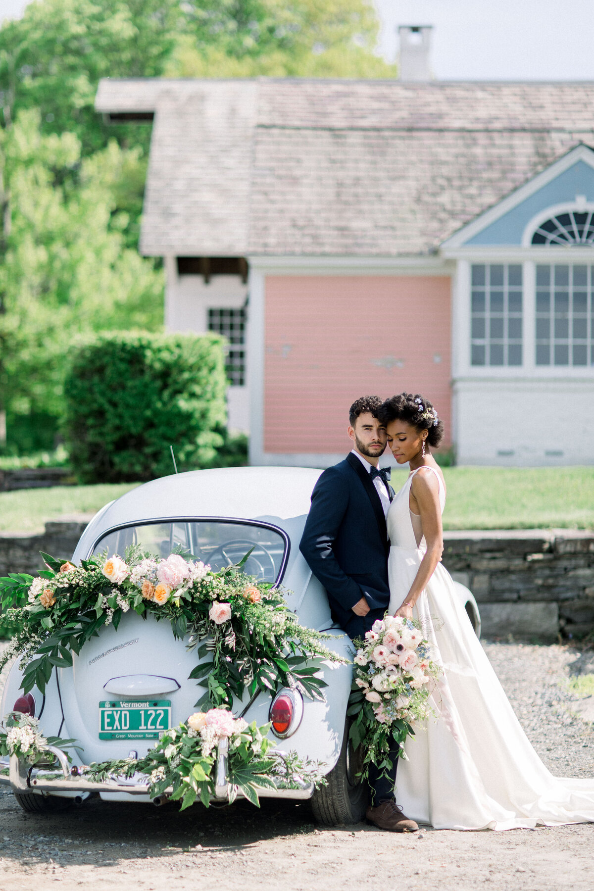 Bride and groom by a car covered in florals at The Estate at North Mowing