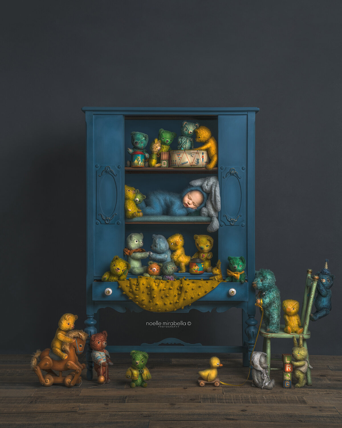 Blue vinatge cabinet full of bears with a sleeping baby on the shelf.