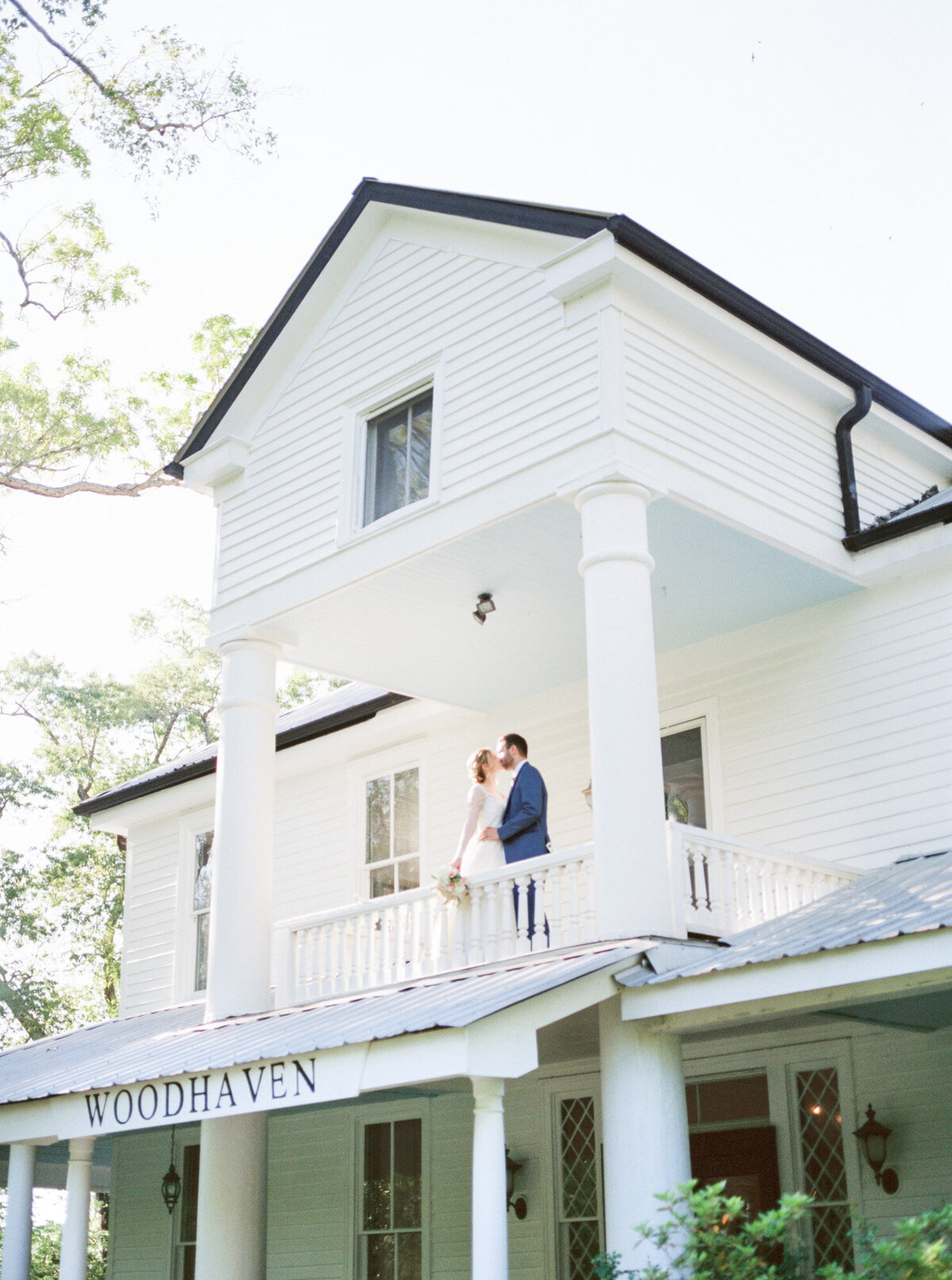 A bride and groom share a kiss on the balcony of a historic home by Birmingham wedding photographer, Kelsey Dawn Photography