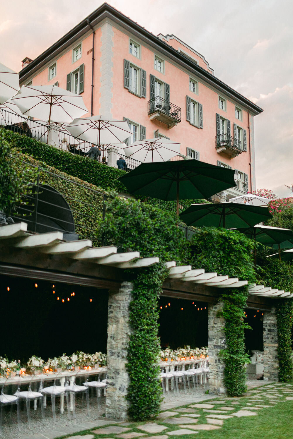 Lake Como Wedding Reception white florals long table under green roof and pink villa