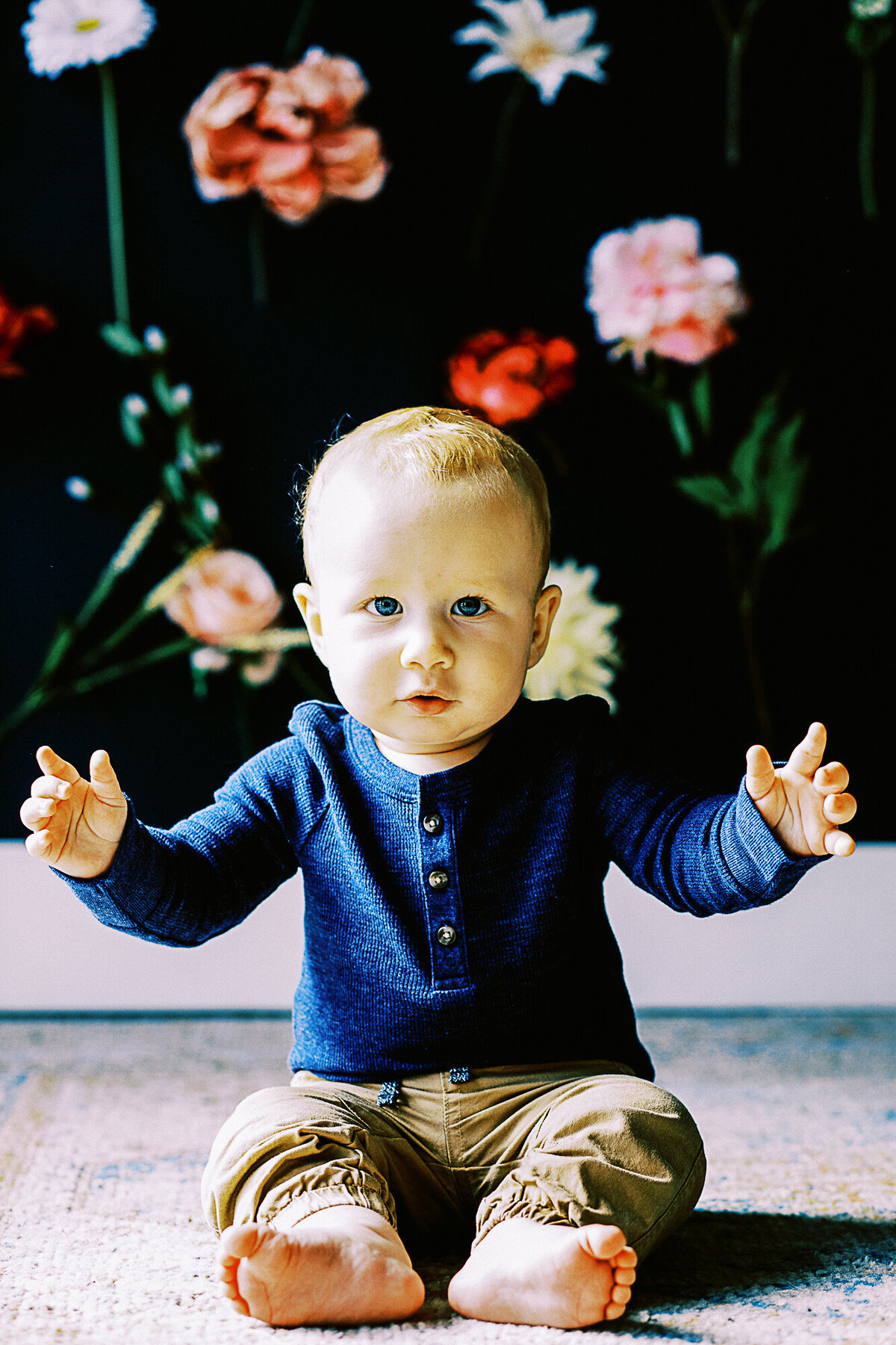 baby boy with blue eyes and blue shirt looks at camera