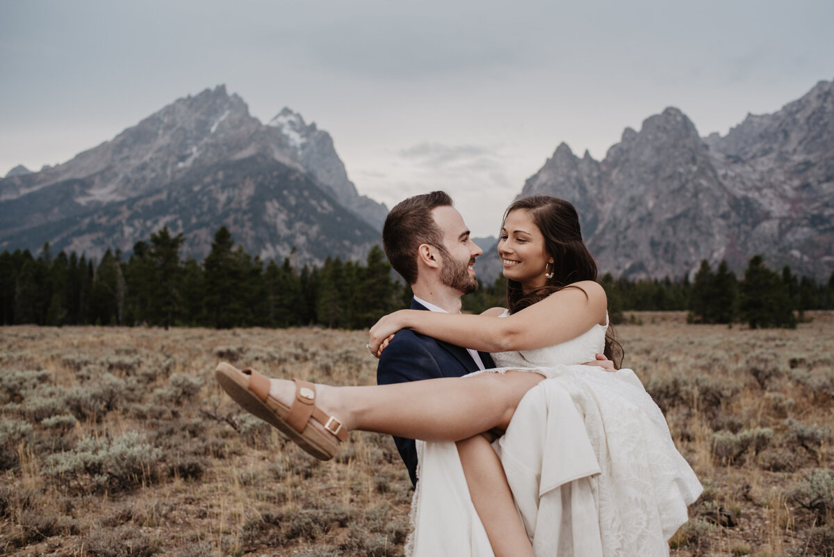 Photographers Jackson Hole capture groom lifting bride in front of Tetons