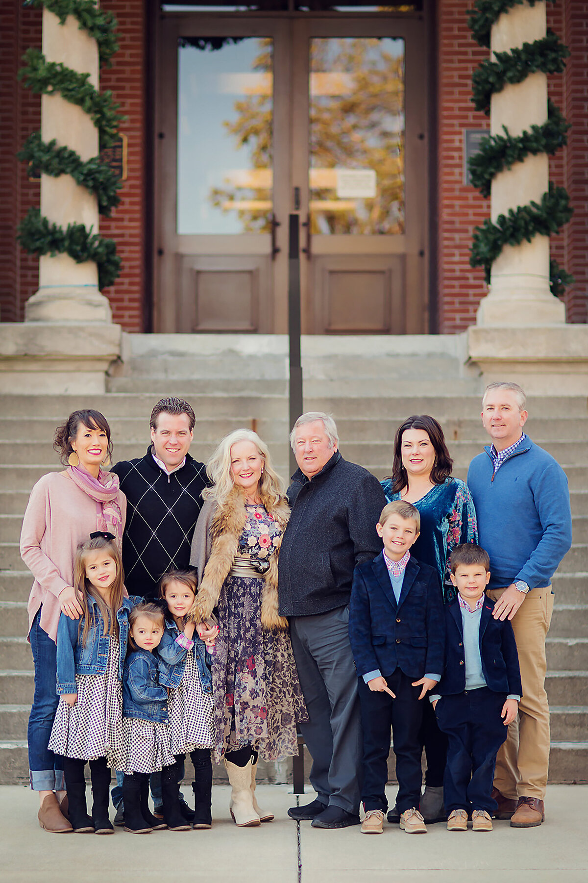 Group photograph of an extended family in downtown Franklin around Christmas time. They are dressed up in front of a building decorated with garland.