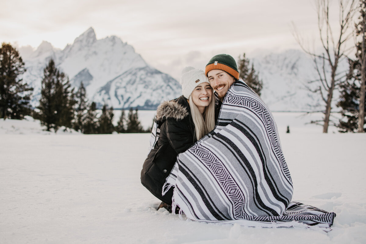 engaged couple in Jackson Hole  as they crouch next to each other and smile photographed by jackson hole photographers