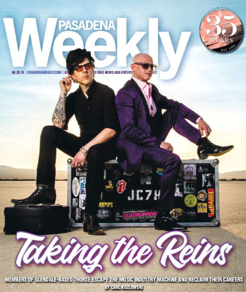Magazine article Pasadena Weekly featuring band 7Horse photo of duo sittings on guitar case with stickers in desert