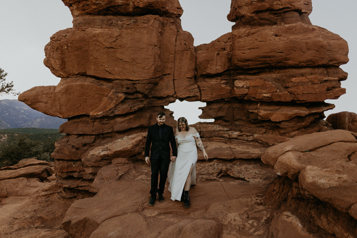 newlyweds standing between red rocks at Garden of the Gods in Colorado