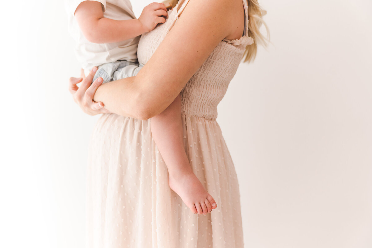 Expectant mom holds toddler on her tummy in a close embrace.  Taken by Minneapolis Maternity Photographer, Fig and Olive Photography.