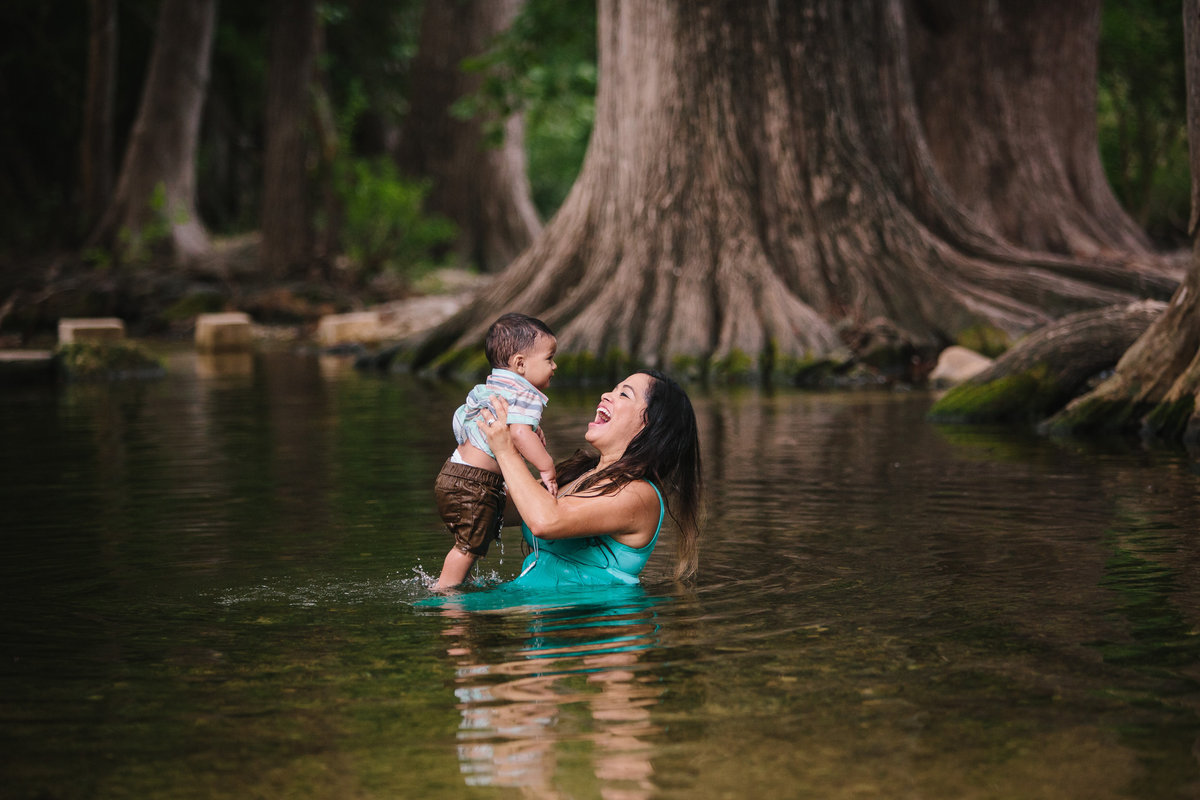 mother holding her son while sitting in a river