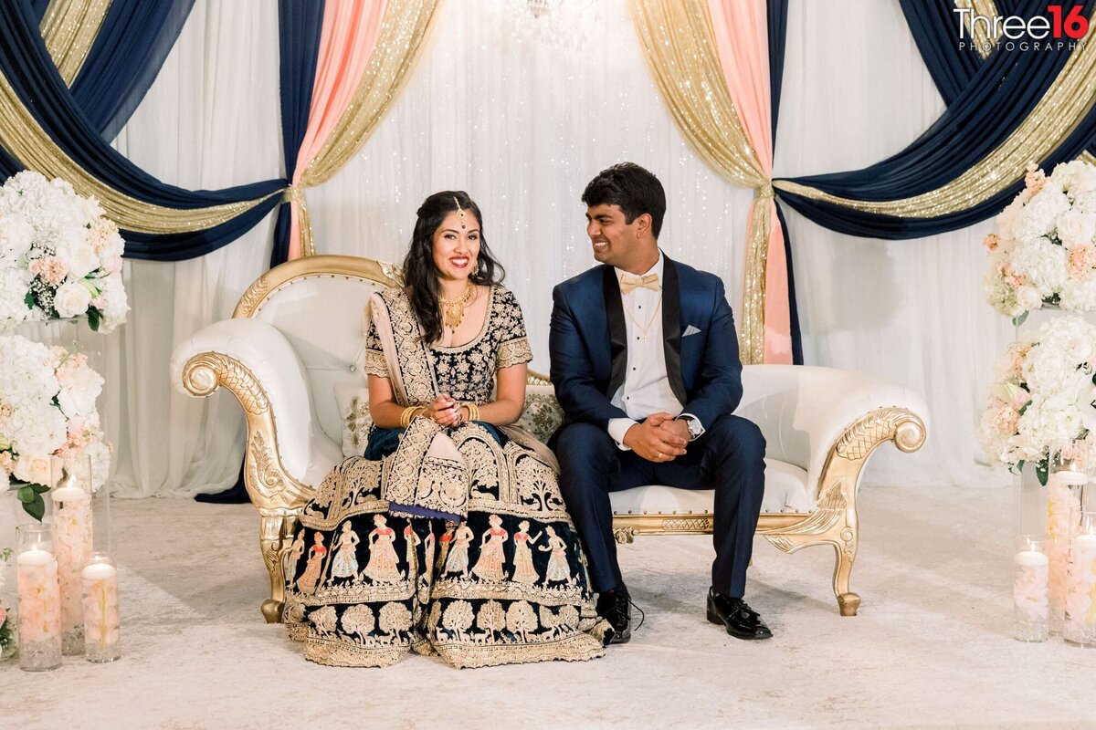 Bride and Groom sit together on a love seat during the reception