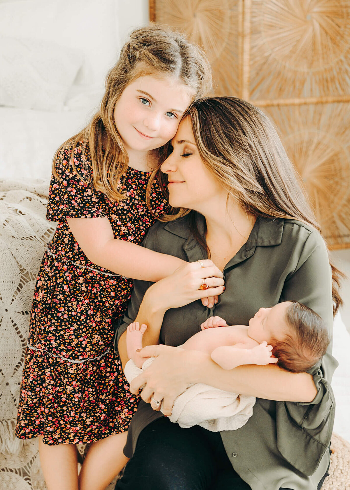 mom snuggles oldest daughter while holding baby for newborn photos in jackson missouri