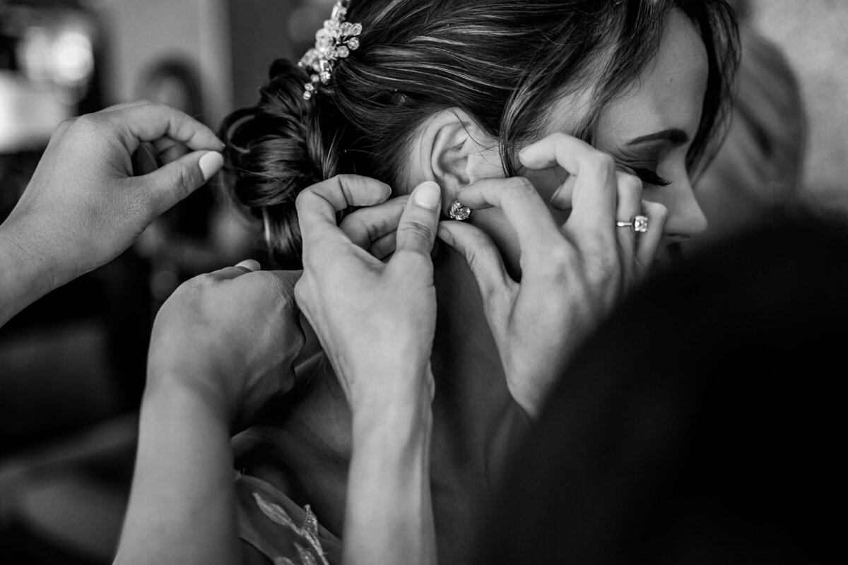 bridesmaids helping bride put on  her family heirloom earrings
