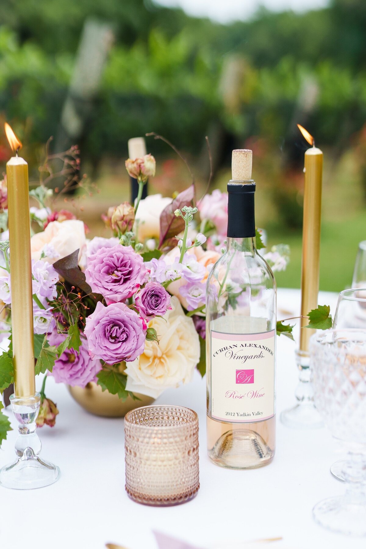 A closeup photo featuring a bottle of wine and lavender and gold accents at a vineyard wedding near Charlotte, NC.