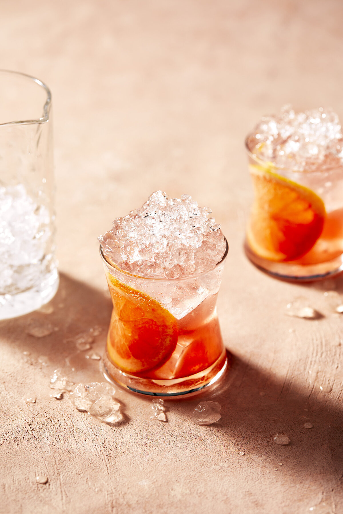 Two small glasses filled with ice and fruit.
