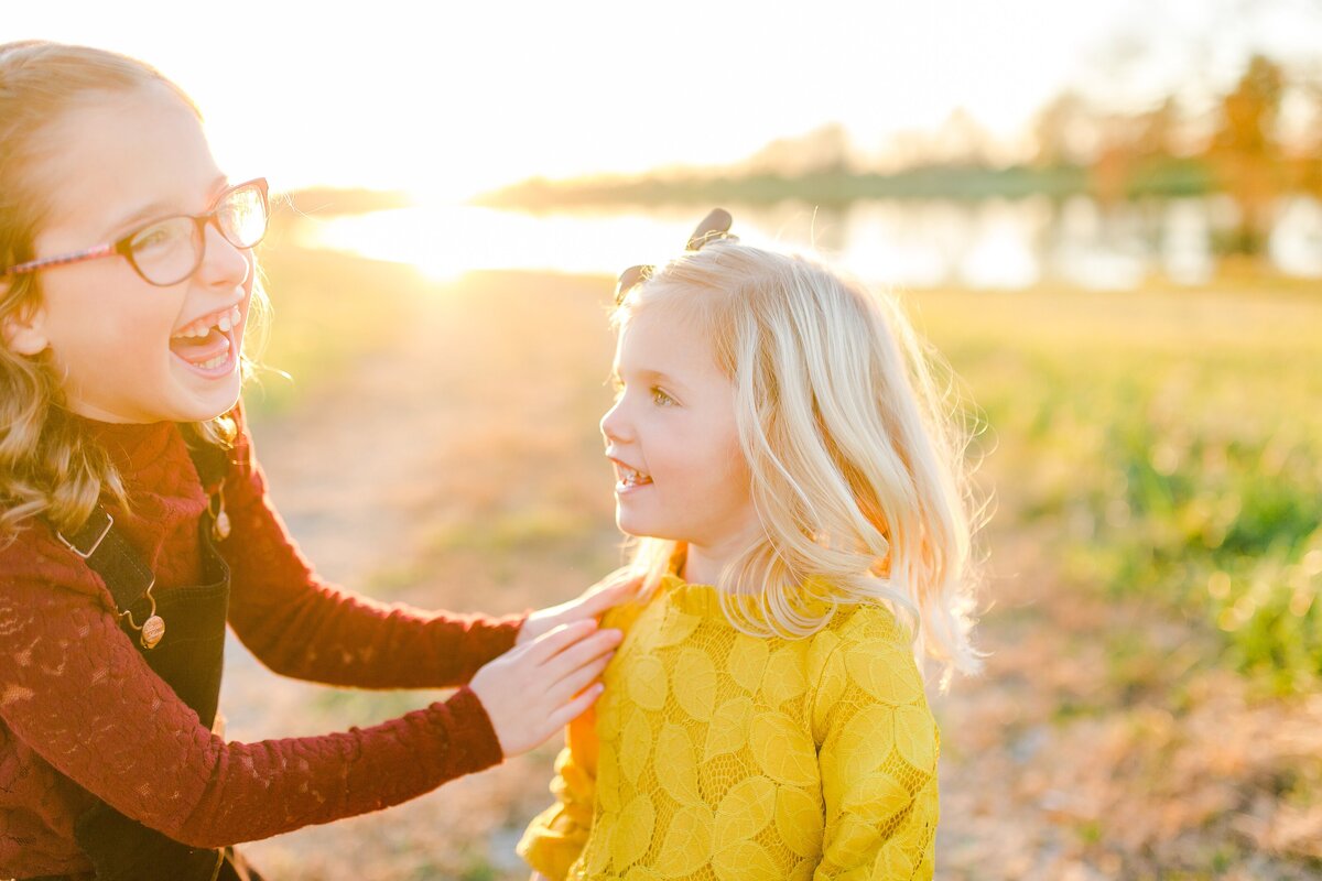 Two sisters laughing at sunset in a field in Lexington KY during a photo session.