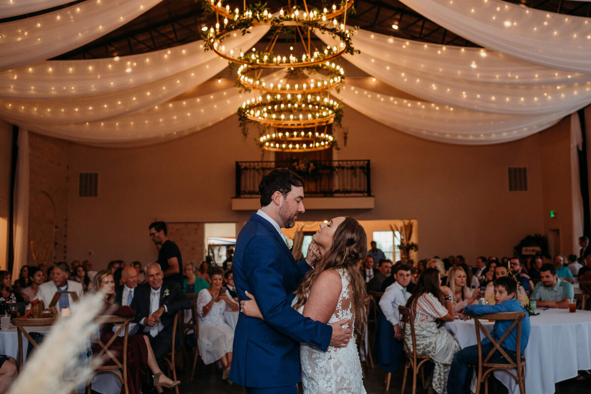 Photo of a bride and groom during their first dance inside of a Tennessee wedding venue with chandeliers