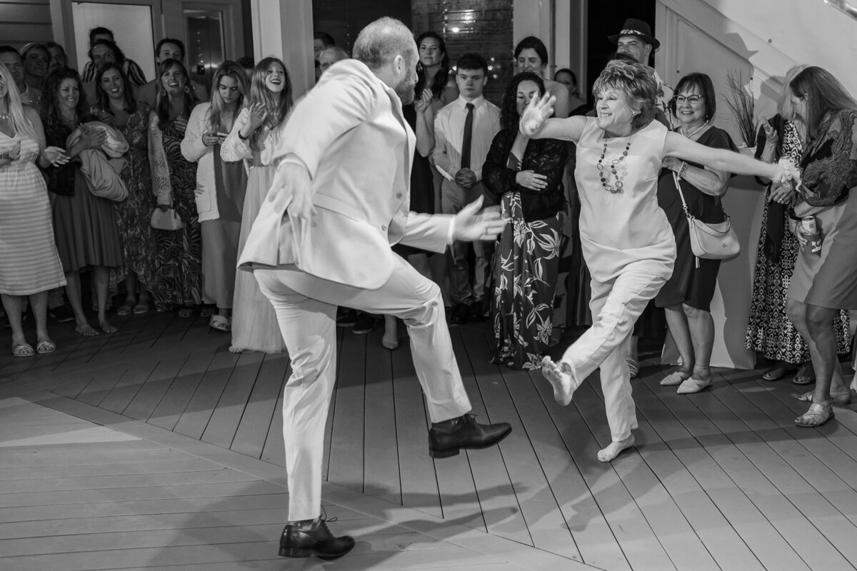 The mother of the groom dancing with her son during his wedding reception enjoying their Raleigh wedding photos