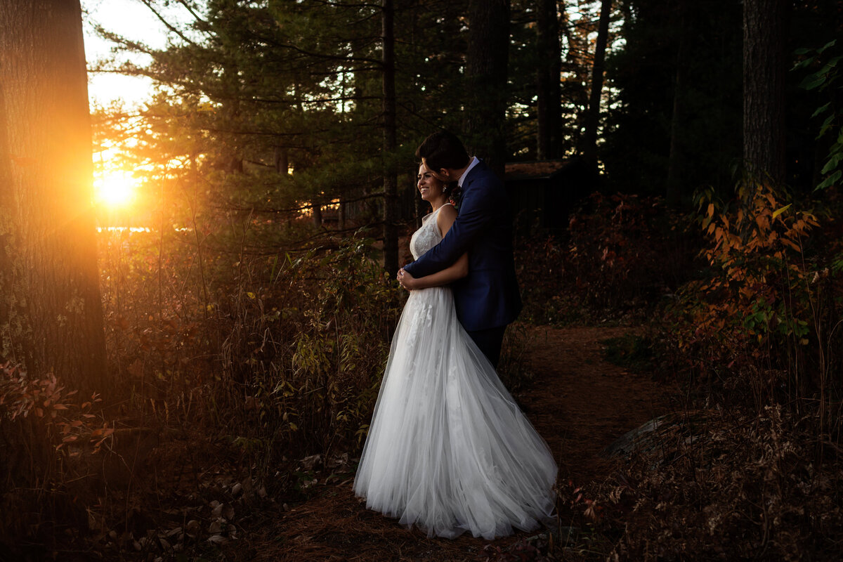 Late fall wedding at Migis Lodge in Maine with the sun setting behind the couple