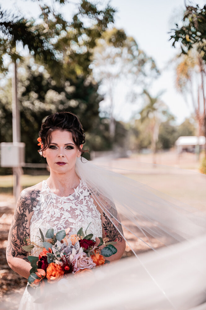 bride in her wedding gown looking at the camera with her veil blowing in front of her - Townsville Wedding Photography by Jamie Simmons