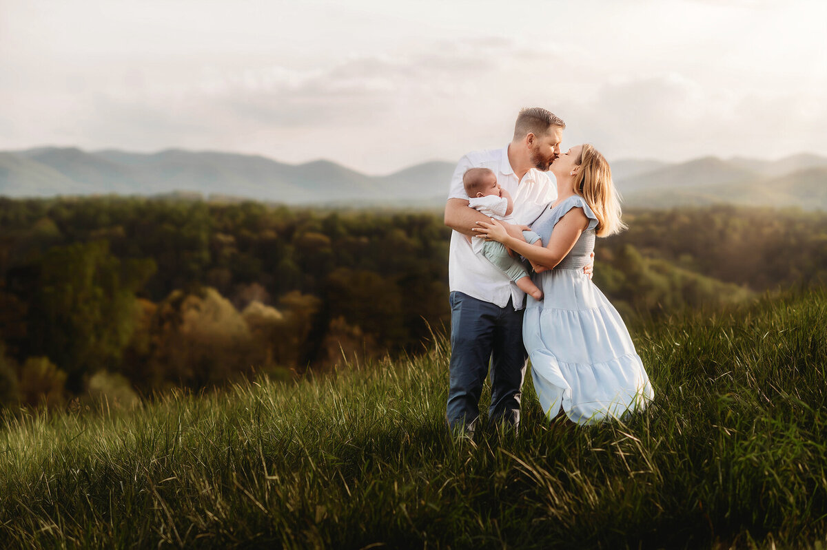 Parents embrace their baby on a mountain top during Family Photos in Asheville, NC.