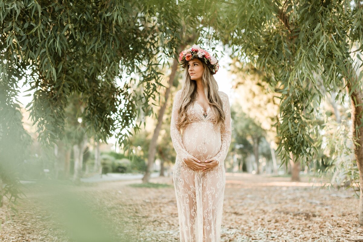 Pregnant woman in peony flower crown in eucalyptus forest