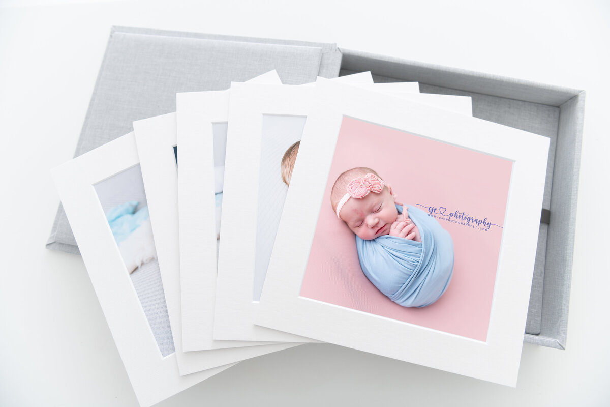 A series of newborn photos printed and spread across a grey box