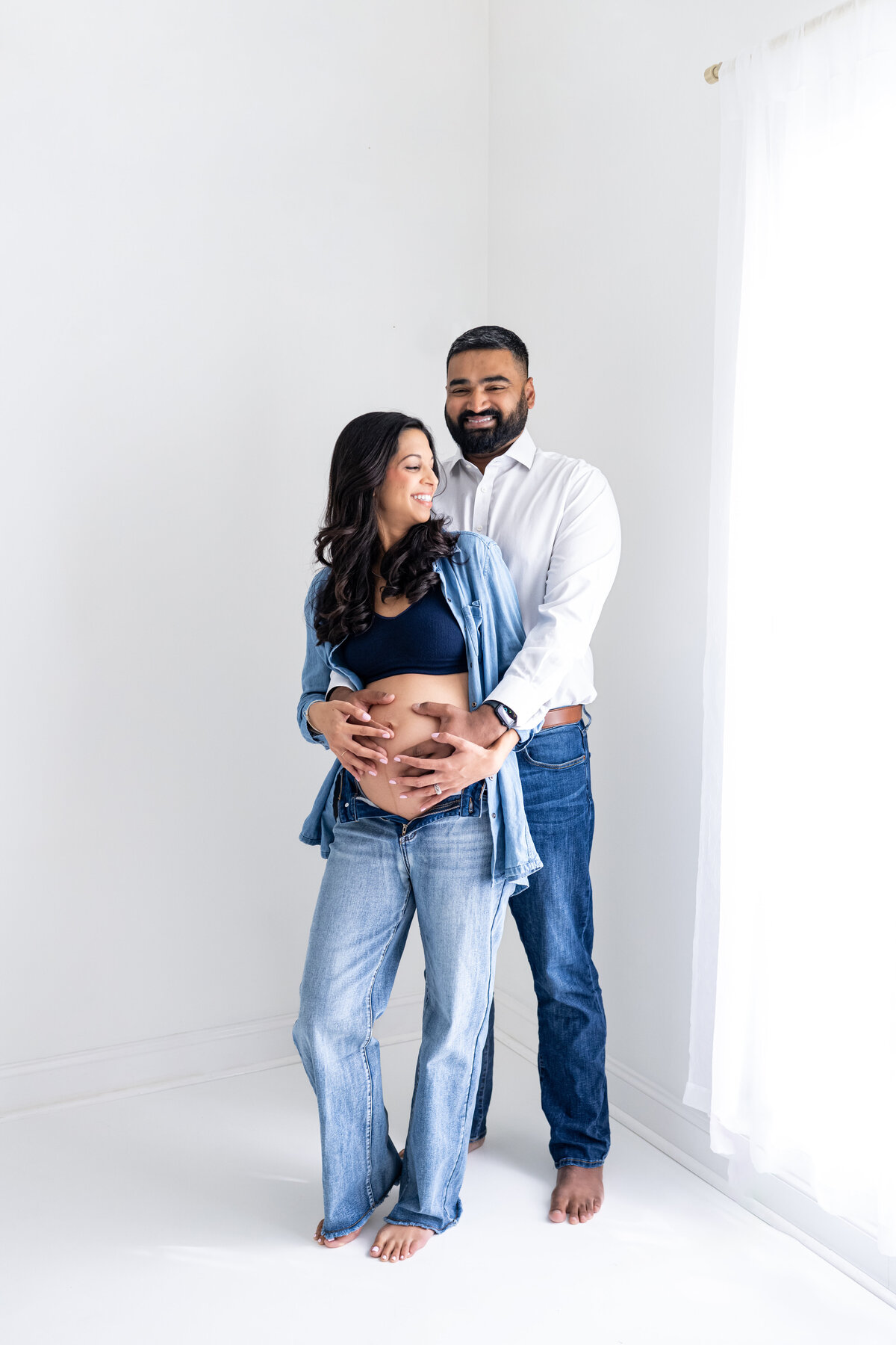A husband and wife posing together for their maternity pictures