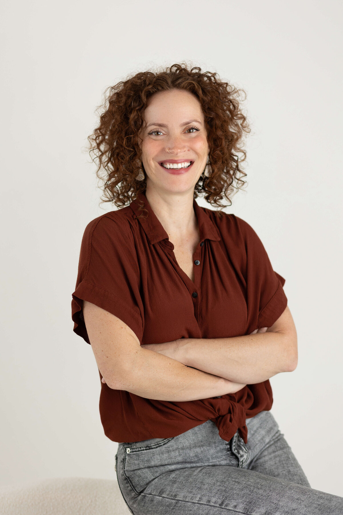 Curly haired woman smiling on a white backdrop