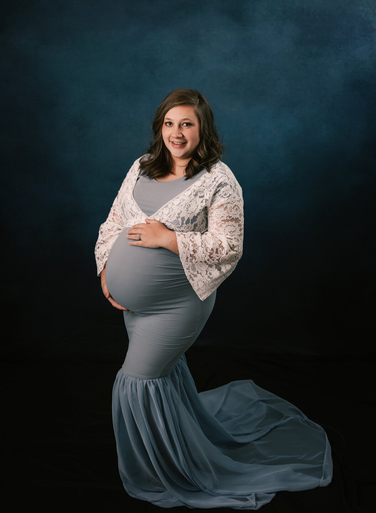 A full length portrait of a pregnant mother in a studio setting.